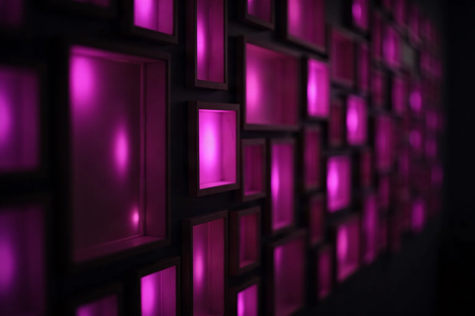 A wall of small empty picture frames in a dark room, each glowing faintly pink